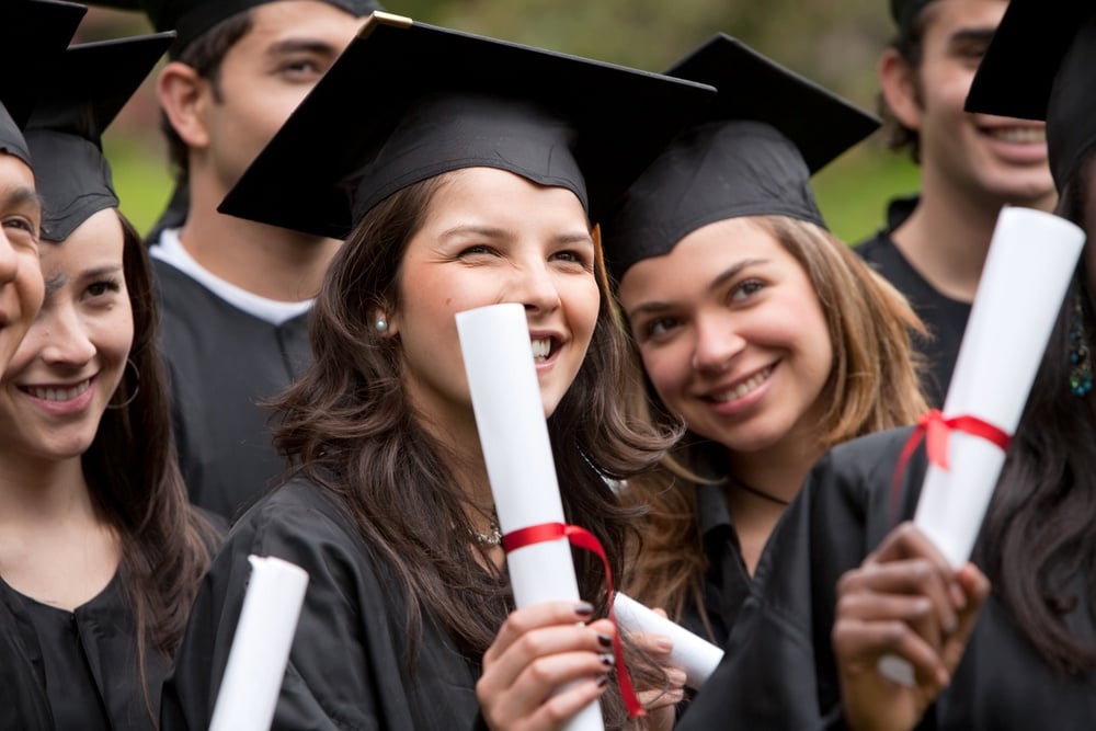 Group of graduation students with diplomas outdoors