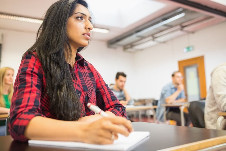 Young female student with others writing notes in the classroom.jpeg